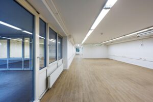 Leeg en licht kantoorpand aan de Prins Hendrikkade met houten vloer en grote ramen.